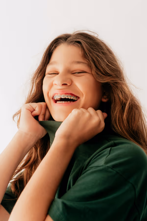 Menina sorrindo e exibindo aparelho ortodôntico